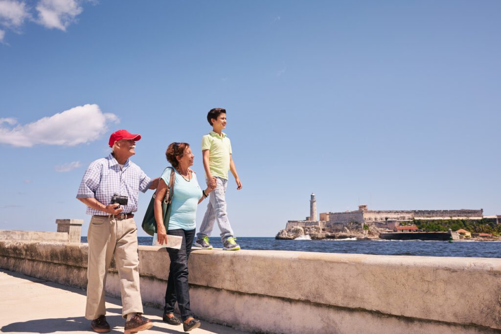 In Havana, Cuba, a joyful Hispanic family, spanning generations, strolls along the iconic Malecon, their smiles radiant with the shared delight of holiday adventures and cherished memories.