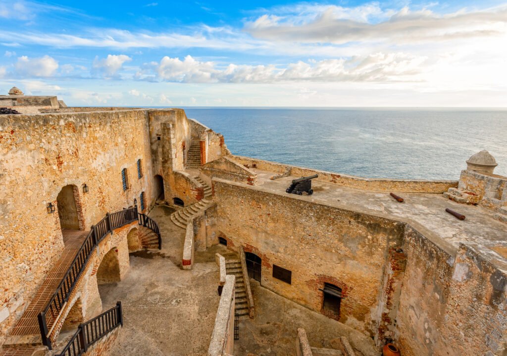 Within the majestic San Pedro de La Roca fortress in Santiago De Cuba, Cuba, the inner yard is bathed in the warm glow of sunset, casting an enchanting aura upon its ancient walls, echoing centuries of history.