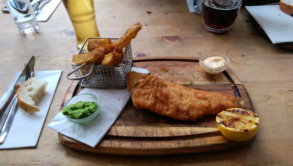 Indulge in the quintessential British delight: classic fish 'n chips, served hot and crispy from a traditional London pub, a timeless taste of culinary comfort.
