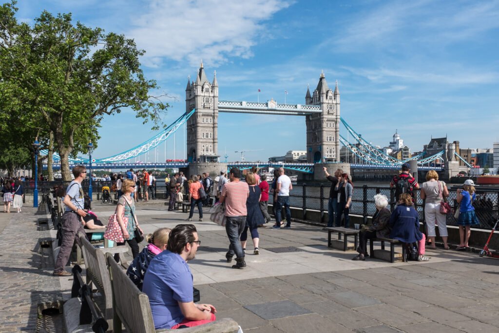 In central London, tourists line the north bank of the River Thames, gazing upon the majestic Tower Bridge, a timeless symbol of the city's grandeur and history.