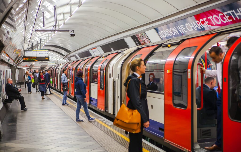 In London, UK, commuters patiently wait on the underground tube platform, anticipation in the air as they await the arrival of their train, a familiar scene in the bustling rhythm of the city.