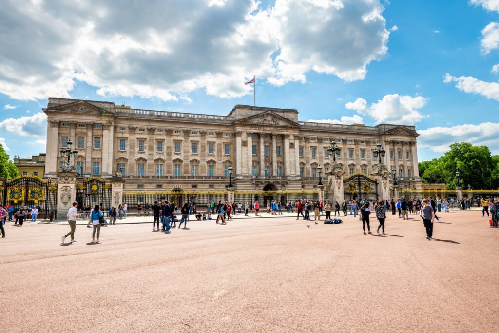 Buckingham Palace: Royal residence and tourist magnet, where crowds gather to capture moments in the summer sun, epitomizing London's regal allure and vibrant atmosphere.
