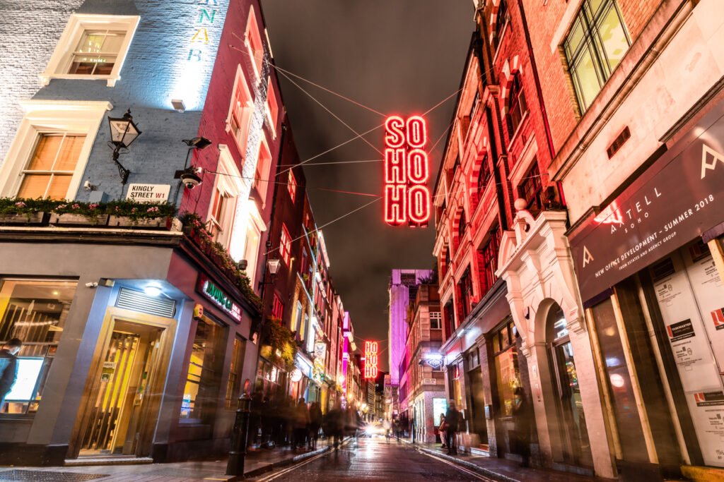 Soho during Christmas: A festive spectacle, with dazzling lights adorning streets, merry-go-rounds, and joyful crowds, exuding the holiday spirit in the heart of London, United Kingdom.