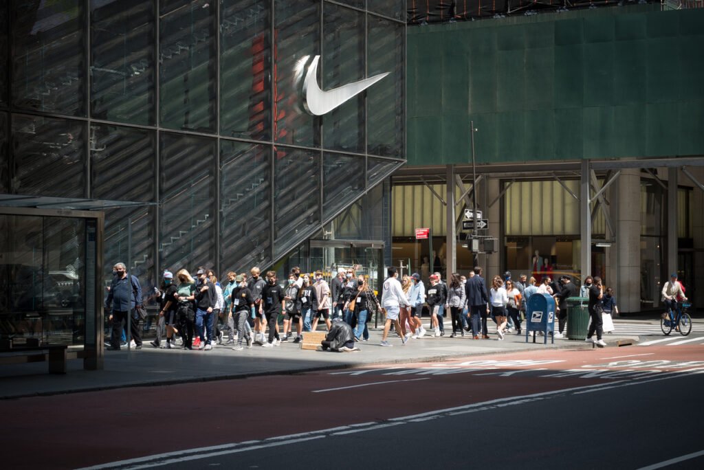 Midtown Manhattan: Tourists stroll past the iconic Nike store on Fifth Avenue, amidst the bustling energy of one of New York City's most vibrant neighborhoods.