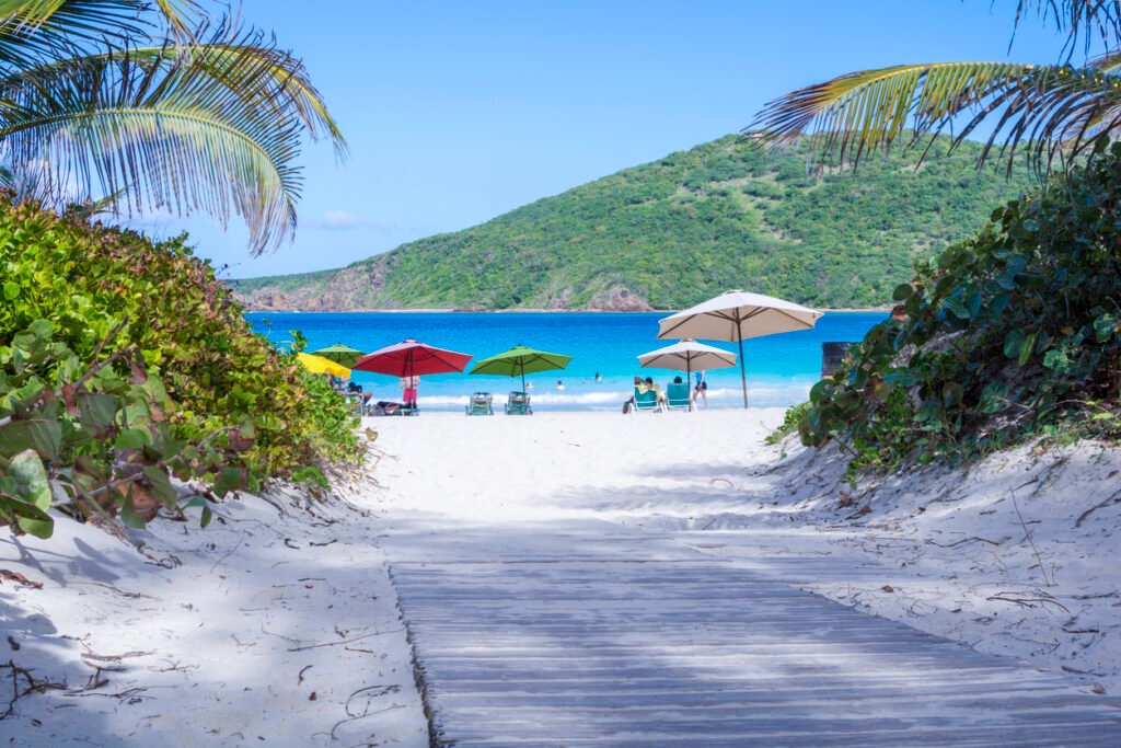 A wooden walkway guides visitors to the stunning Flamenco Beach on the picturesque Puerto Rican island of Culebra, where pristine tropical sands meet crystal-clear waters in a breathtaking union of natural beauty.
